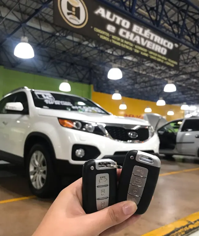 Duas chaves presença na mão, com um SUV branco ao fundo na loja da i9 no Auto Shopping Global